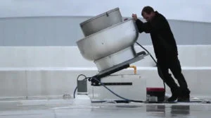 Technicien refermant un ventilateur sur un toit
